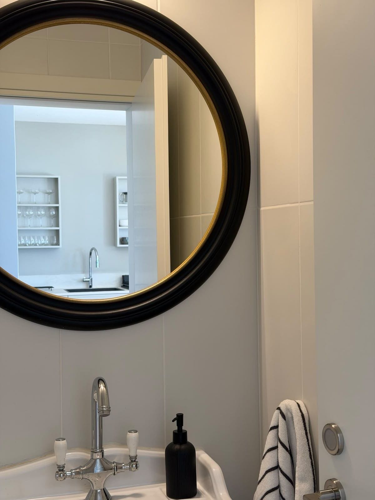 David HaMelech — Sink and round mirror in the bathroom