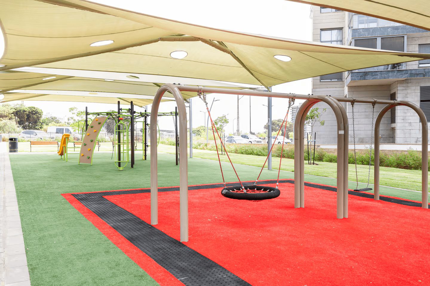 Shaded children's playground beside the Park & Sea Tower apartment building in Netanya